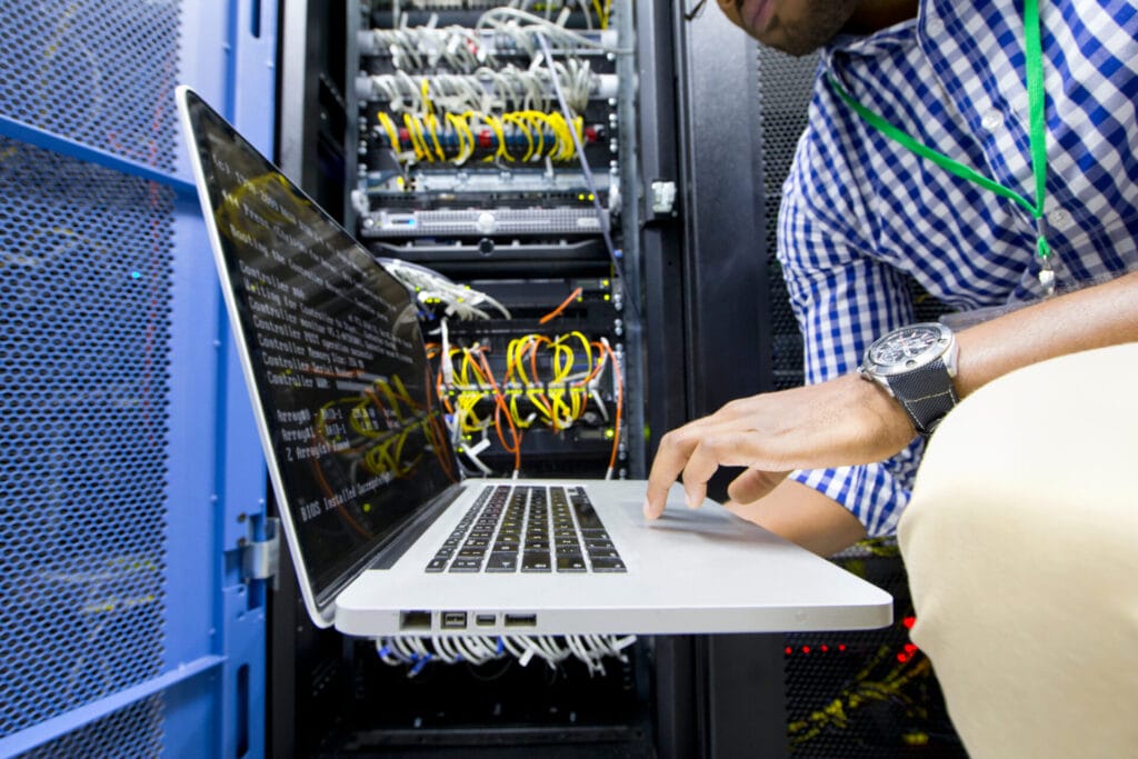 IT technician working on laptop in a server room